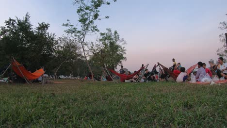 Medium-Exterior-Time-Lapse-Shot-of-Many-Families-Having-Picnics-and-Relaxing-With-Hammocks-in-the-Grassy-Park-with-Road-in-the-Background-in-the-Daytime