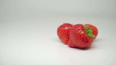 Three-Sweet-Red-Strawberries-Fruits-At-the-Top-of-The-Turn-Table---Close-Up-Shot