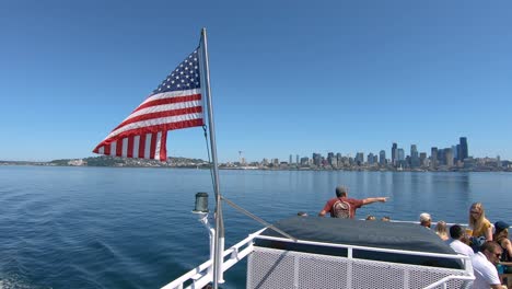 Rückseite-Der-Yacht-Mit-Amerikanischer-Flagge-Und-Stadt-Seattle-Im-Hintergrund,-Zeitlupe