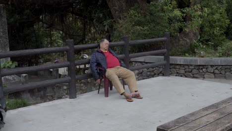 Un-Hombre-Durmiendo-En-Una-Silla-En-Un-Estacionamiento-Taiwanés---Tiro-Ancho
