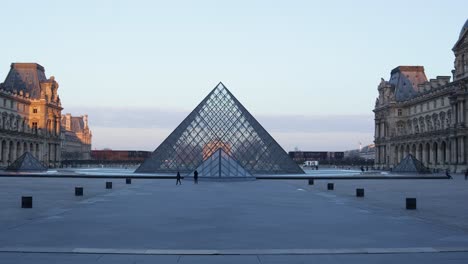 Slow-dolly-in-wide-shot-of-the-Louvre-museum-pyramid-and-palace-court-during-early-morning-with-two-people-in-the-shot