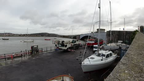 Hydraulic-crane-vehicle-lifting-heavy-fishing-boat-vessel-into-Conwy-harbour-water-timelapse