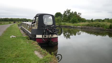 British-canal-narrow-boat-moored-along-scenic-English-marine-countryside-waterway