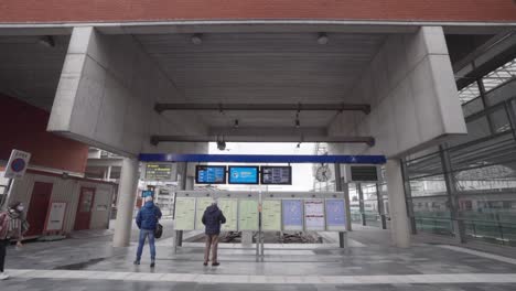 Passagiere,-Die-Auf-Die-Elektronische-Abflug--Und-Ankunftstafel-Schauen,-Bahnhof-Leuven