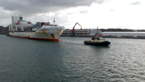 Rising-tilt-down-shot-cargo-ship-sailing-Antwerp-port-birds-fly-by-cloudy-day