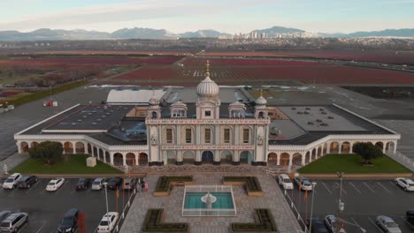 Imágenes-De-Drones-4k-Fachada-Frontal-Del-Templo-Sikh-Con-Hermosa-Escultura-Elaborada-Arquitectura-Simétrica-En-Medio-De-Tierras-De-Cultivo-Que-Revelan-Los-Campos-De-Arándanos-Y-Estacionamientos-Alrededor-Del-Edificio