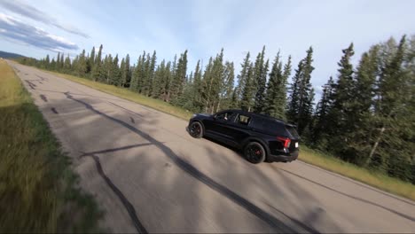 Dropping-in-from-the-tree-tops-with-a-drone-close-up-to-a-vehicle-driving-on-a-road