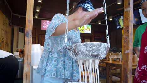 Mujer-Haciendo-Fideos-Chinos-Tradicionales-En-El-Puesto-De-Comida-En-El-Casco-Antiguo-De-Feng-Huang