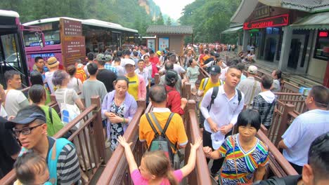Crowds-of-people-leaving-the-Ten-Mile-Gallery-exit-in-the-Zhangjiajie-national-park-and-queuing-for-the-buses,-Hunan-Province