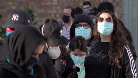 People-in-protective-face-masks-queue-up-outside-an-appointment-only-Covid-19-testing-centre