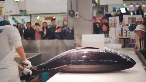 Cutting-Off-The-Tail-Of-A-Bluefin-Tuna-By-A-Cleaver-Knife-With-Crowd-Of-People-Watching-In-Toretore-Ichiba-Fish-Market,-Wakayama-Japan