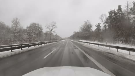 Los-Copos-De-Nieve-Caen-En-Un-Parabrisas,-El-Auto-Conduce-Rápido-En-Una-Autopista-Alemana-En-La-Temporada-De-Invierno,-Un-Video-Suave-De-4k