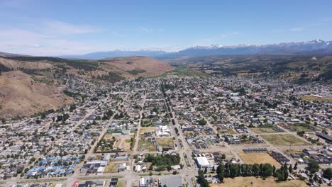 Dolly-in-flying-over-Esquel-city-with-Andean-mountains-in-background,-Patagonia-Argentina