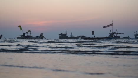 Fishing-boats-silhouettes-with-a-small-waves-and-colorful-skies-docked-near-a-shore-video-background