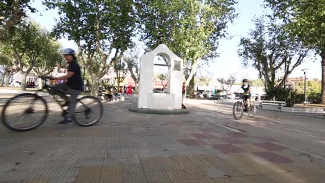 Chicos-Montando-En-Bicicleta-En-La-Plaza-Del-Pueblo-Con-Un-Día-Soleado