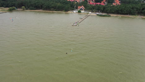 Antenne:-Rotierende-Aufnahme-Eines-Jungen-Surfers,-Der-Sich-In-Der-Bucht-Der-Ostsee-Ausruht