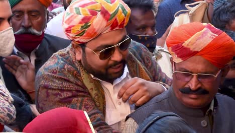 man-wearing-colorful-turban-passing-through-crowd-of-people-for-permission-to-enter-the-coronation-ceremony