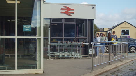 Junge-Und-ältere-Menschen,-Die-Schutzmasken-Tragen,-Verlassen-Und-Betreten-Den-Bahnhof-In-England