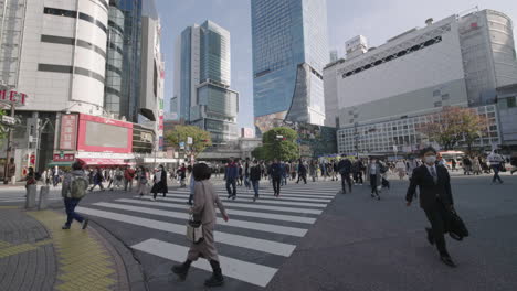 Japanische-Einheimische-An-Der-Scramble-kreuzung-Mit-Hochhäusern-Im-Hintergrund-An-Der-Shibuya-kreuzung-In-Tokio,-Japan-Während-Einer-Pandemie
