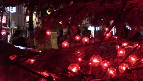 Zoomen-Auf-Eine-Person,-Die-Fotos-An-Einem-Weihnachtsbaum-In-Der-Grafton-St-Macht,-Mit-Lichtern-Um-Sie-Herum-Und-Menschen-Im-Hintergrund