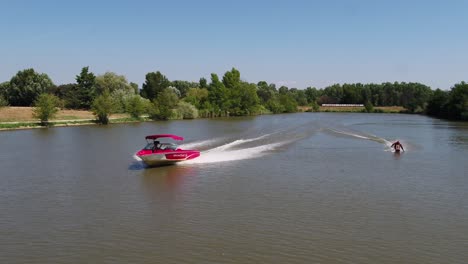 Luftaufnahme-Eines-Bootes-Und-Eines-Mannes-Beim-Wakeboarden---Zeitlupe,-Zurückziehen,-Drohnenaufnahme