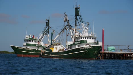 Establishing-Shot,-Scenic-view-of-ripple-on-the-blue-sea-on-as-a-sunny-day-in-Adolfo-Lopez-Mateos-Baja-California-sur,-Mexico,-Two-fishing-boats-parked-at-the-docks-in-the-background