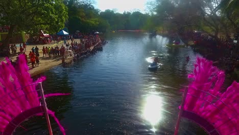 Aerial-flyover-aquatic-carnival-parade-during-summer-with-celebrating-people-on-shore-in-city-of-Penonome-in-Panama