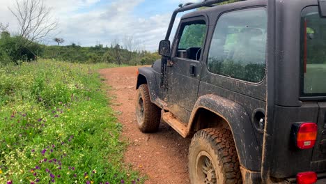 Adventure-4x4-wrangler-jeep-on-mountain-dirt-road,-fun-expeditions-in-the-countryside,-4k-camera-tilting-up