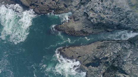 Aerial-of-coastal-rocky-area-tracking-sideways-inland-across-an-inlet-cave-that-carves-far-into-the-headland-in-Sutherland-Scotland