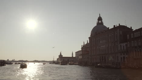 Sailing-towards-Basilica-di-Santa-Maria-della-Salute-on-a-beautiful-sunny-morning,-water-reflections,-Venice,-Italy