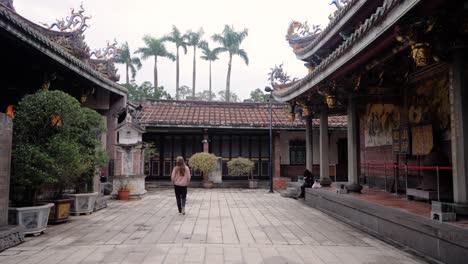 Slow-motion-shot-of-caucasian-woman-tourist-walking-and-looking-at-Dalongdong-Baoan-Temple-in-Taipei,-Taiwan