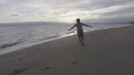 Dancer-jump-on-beach,-sunrise-in-background