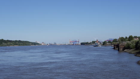 Two-ferries-crossing-each-other-on-Elbe-River-at-jetty-Rueschpark-in-Hamburg,-Germany-at-sunny-day