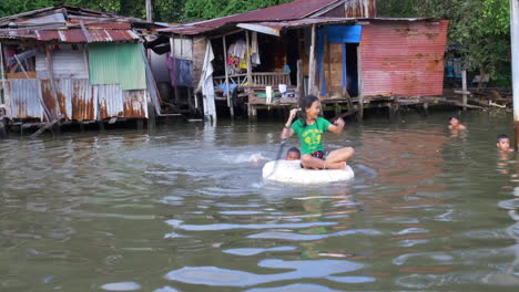 Dos-Niños-En-Bangkok-Jugando-En-El-Agua-Afuera-De-Sus-Casas-Aprovechando-Al-Máximo-Lo-Que-Tienen-En-La-Pobreza