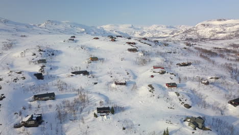 Luftaufnahme-Mit-Vielen-Häusern,-Die-Halb-Im-Schnee-Begraben-Sind,-über-Einer-Kargen,-Bergigen-Winterlandschaft