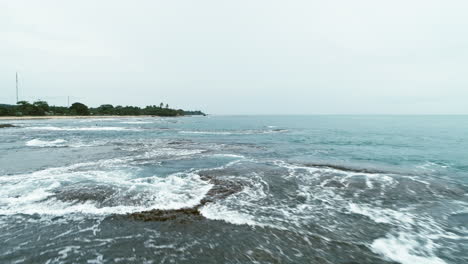 Fliegen-über-Dem-Strand,-Mit-Interessanten-Mustern-Aus-Wellen-Und-Korallen,-Die-Sich-Zu-Einem-Einzigartigen-Bild-Verschmelzen,-Das-In-Der-Gegend-Von-Pelabuhan-Ratu-In-Indonesien-Aufgenommen-Wurde