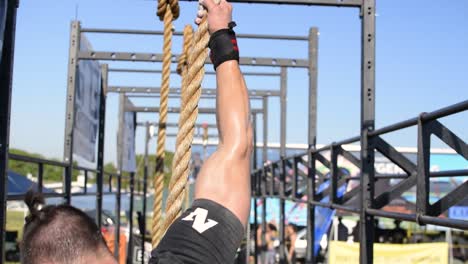 A-fit-athletic,-strong-male-doing-a-military-rope-climb-for-muscular-strength-and-endurance-training,-popular-in-all-armed-forces,-cross-fit-and-assault-course-training-programs