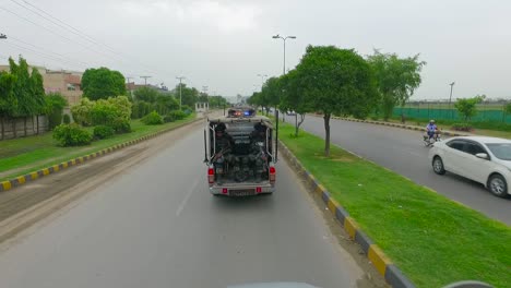 A-security-forces-convoy-is-on-patrolling-in-the-city,-Moving-on-the-road-with-other-traffic,-Aerial-view-from-the-back-side,-commandos-in-the-vans
