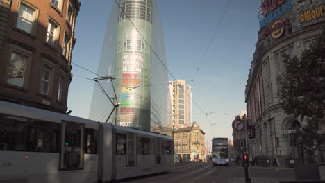 Tram-and-bus-pass-the-National-Football-Museum-in-Manchester-City-centre