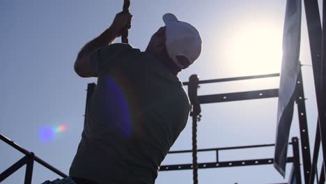 Un-Hombre-Fuerte,-Atlético-Y-En-Forma-Haciendo-Una-Escalada-De-Cuerda-Militar-Para-El-Entrenamiento-De-Fuerza-Muscular-Y-Resistencia,-Popular-En-Todas-Las-Fuerzas-Armadas,-Programas-De-Entrenamiento-De-Cursos-Cruzados-Y-De-Asalto