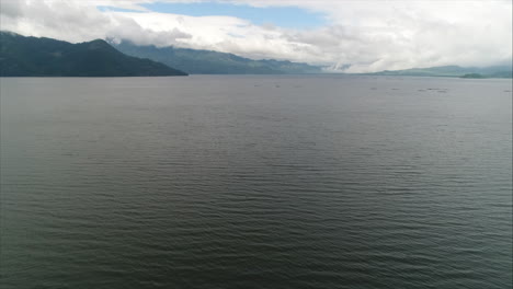 Antena:-Toma-Panorámica-Del-Lago-Rodeado-De-Montañas-Y-Cielo-Azul,-Yojoa,-Honduras