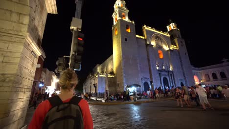 Crowds-of-people-crossing-roads-at-dusk-in-front-of-the-Catedral-de-San-Ildefonso,-Merida,-Yacatan,-Mexico