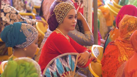 Pretty-woman-in-bright-clothing-fans-herself-in-a-crowd-of-women-gathered-for-an-event-celebrating-National-Women's-Month-in-the-Autonomous-Region-in-Muslim-Mindanao,-Philippines