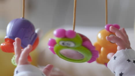 Infant-grabbing-plastic-toys-overhead
