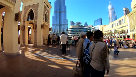 Timelapse-for-Souk-Al-Bahar-bridge-in-front-of-Dubai-mall-with-tourists-walking-by,-photographing-and-enjoying-the-iconic-Burj-Khalifa-and-the-fountain-view