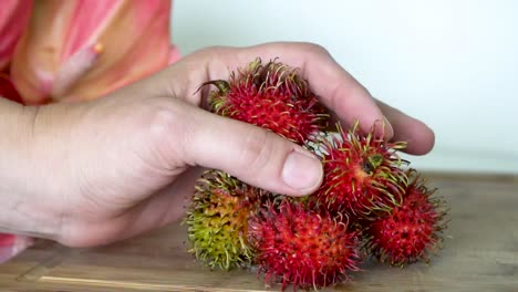 Rambutan-Frucht-In-Der-Hand-Ausgestellt,-Auf-Den-Tisch-Legen