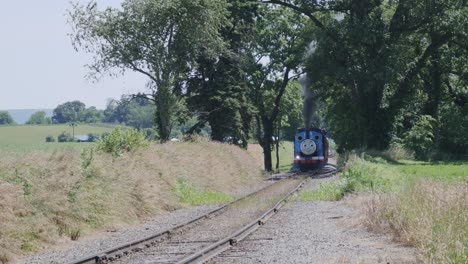 Luftaufnahme-Eines-Thomas-The-Tank-Engine-Mit-Passagierwagen,-Die-Entlang-Der-Amischen-Landschaft-Schnaufen