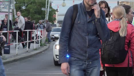 Crowd-of-people-crossing-street-with-police-car-with-blue-lights-and-two-officers-in-a-background