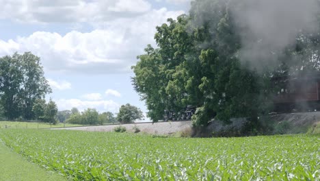 Vintage-Steam-Engine-with-Passenger-Cars-Puffing-along-Amish-Countryside