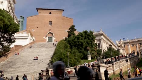 Panning-shot-captures-church-of-Santa-Maria-and-Campidoglio-hill-in-Rome-on-a-busy,-sunny-day